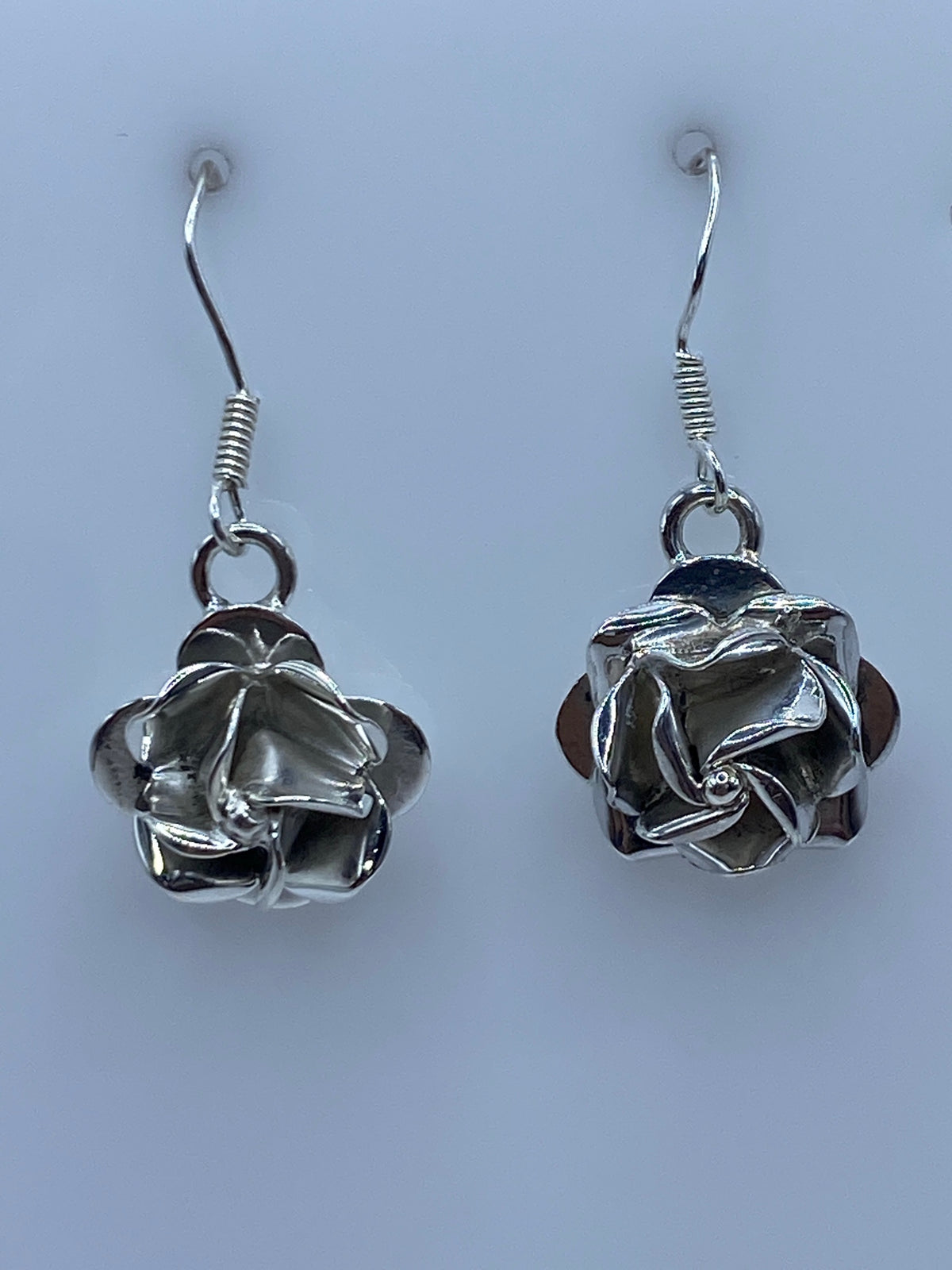 Detalle frontal de los aretes florales repujados mostrando el volumen tridimensional