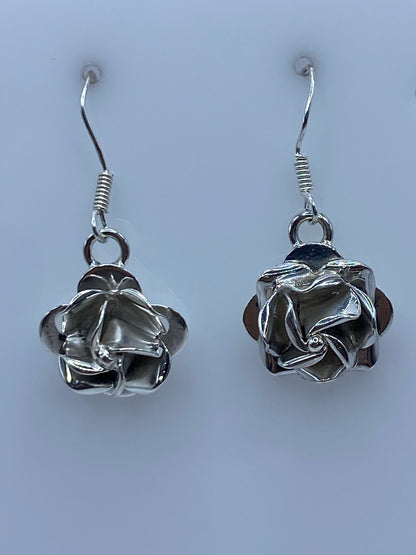 Detalle frontal de los aretes florales repujados mostrando el volumen tridimensional