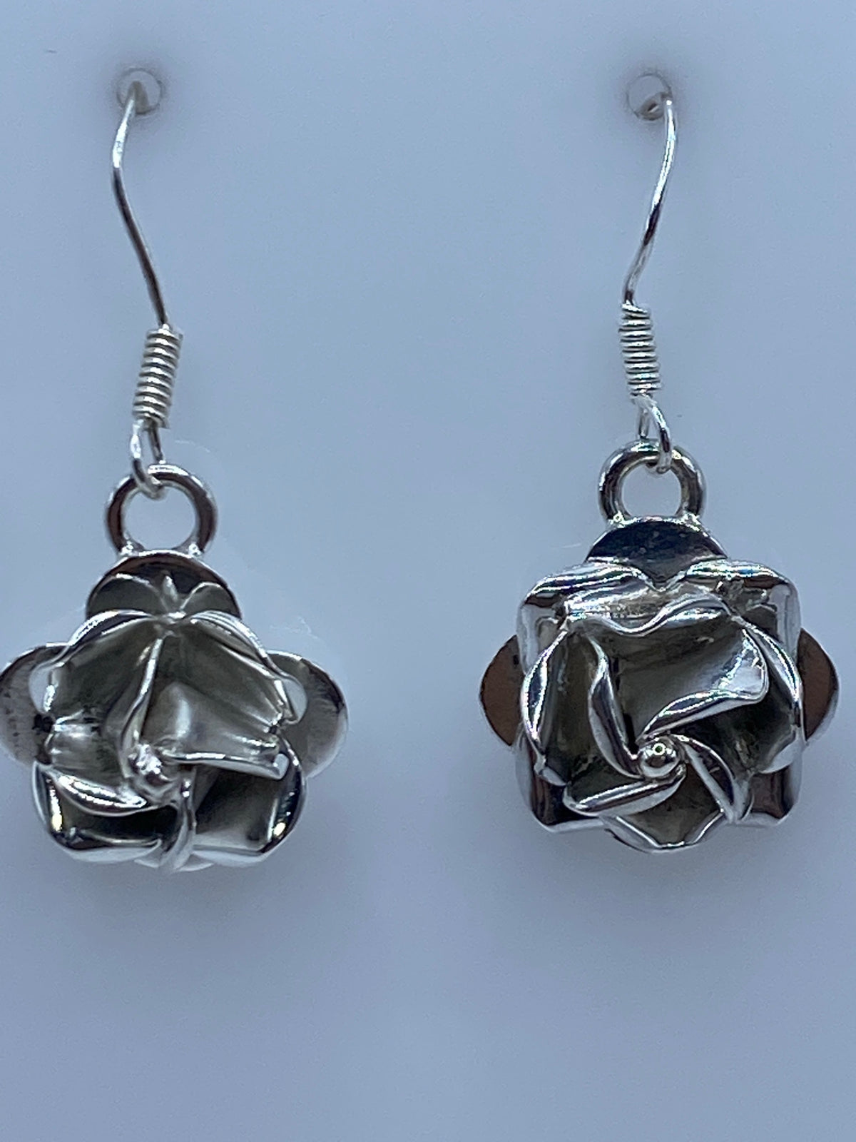 Aretes de plata sobre una regla de centímetros marcando el largo de 2.9 cm