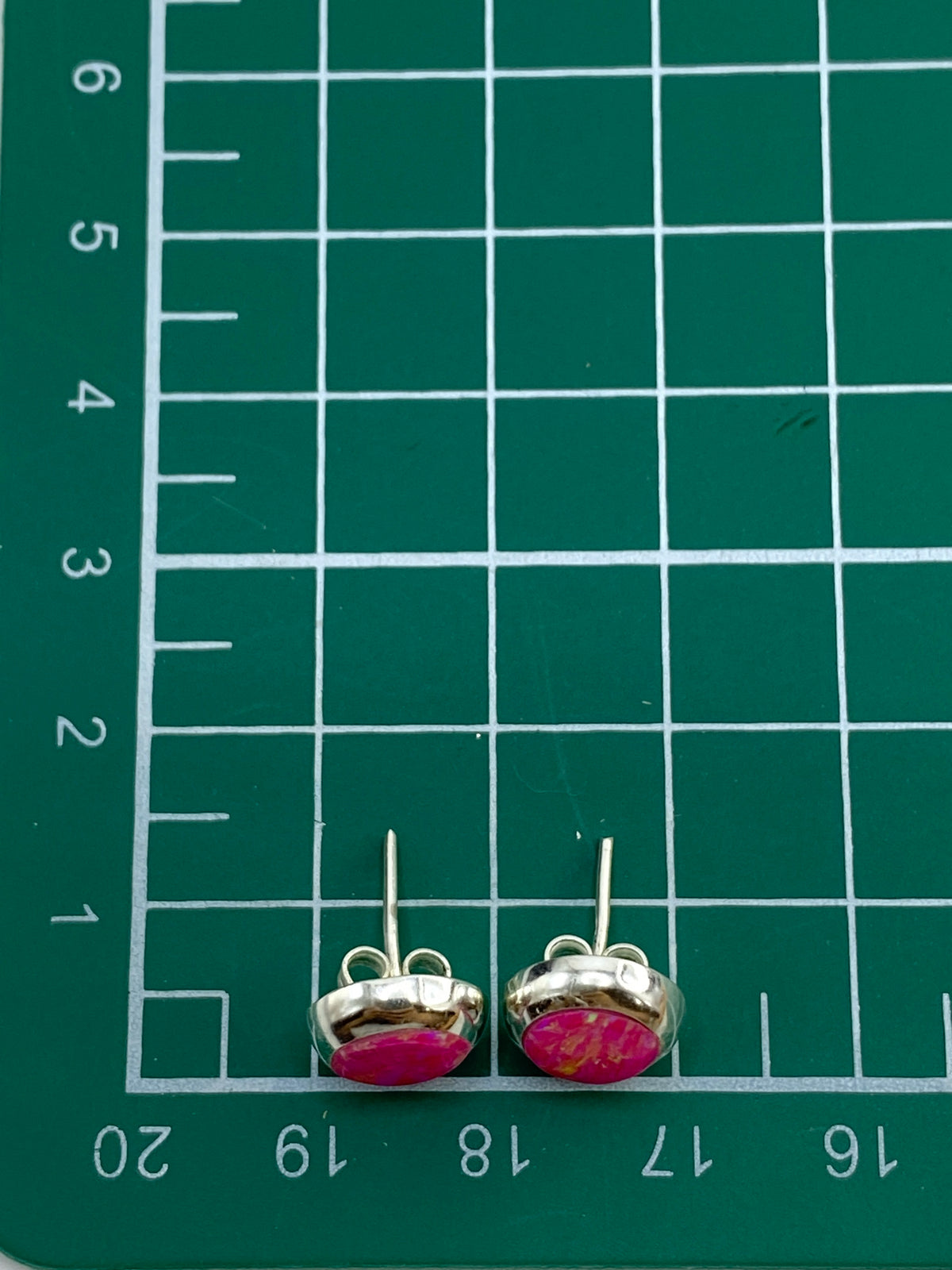 Los dos aretes juntos reflejando luz, mostrando los tonos únicos del fuego del ópalo