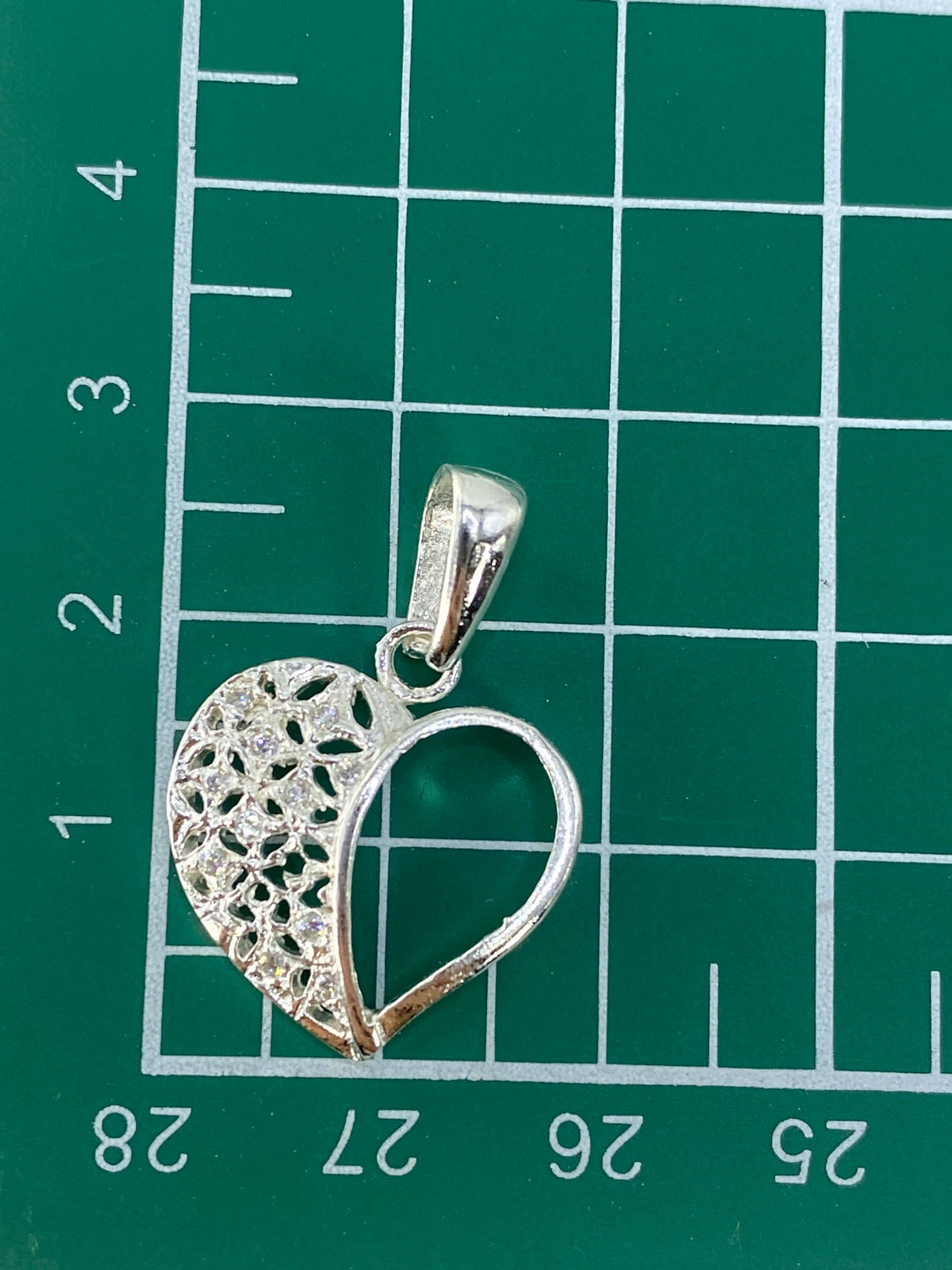 Corazón repujado de plata pura sobre fondo gris, mostrando el peso de 1.8 gramos