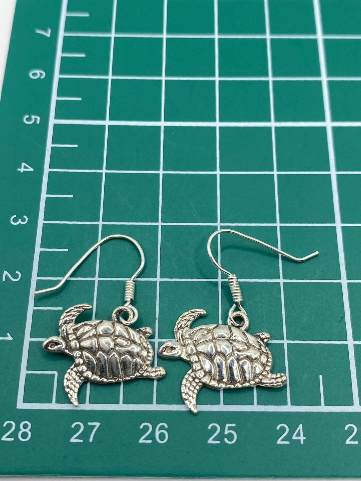 Aretes de tortuga marina en plata 925 sobre fondo blanco con gancho visible