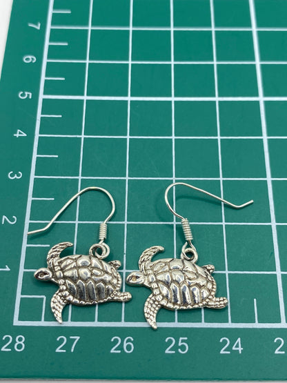 Aretes de tortuga marina en plata 925 sobre fondo blanco con gancho visible