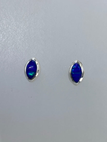 Detalle frontal de un arete mostrando el ópalo multicolor en engaste de plata