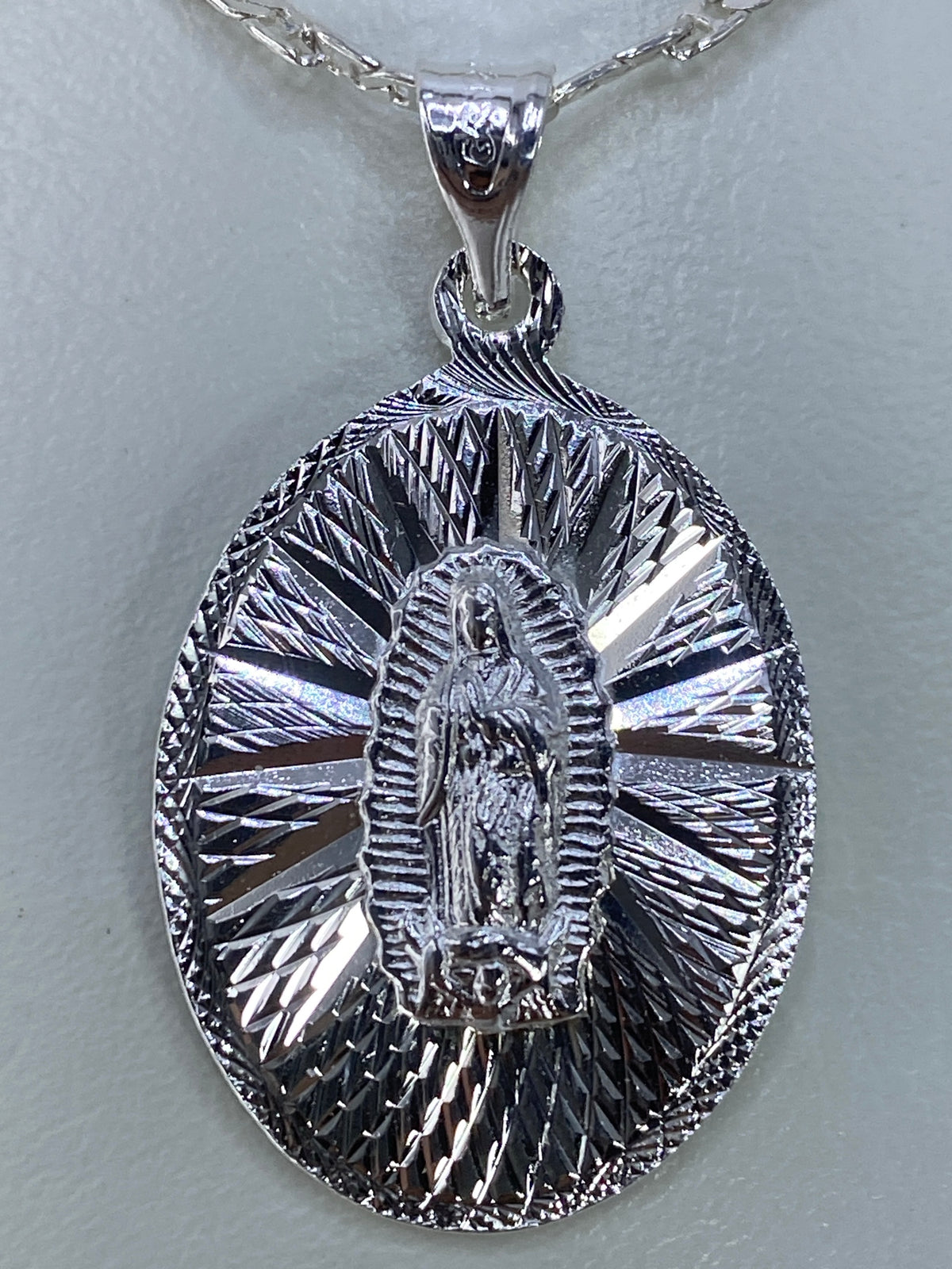 Dije Guadalupano de plata repujada en tamaño natural mostrando el halo radiante