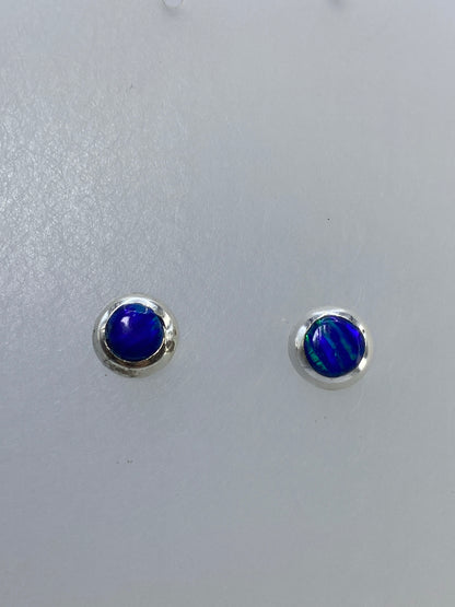 Detalle frontal de los aretes mostrando los reflejos naranjas y dorados del ópalo