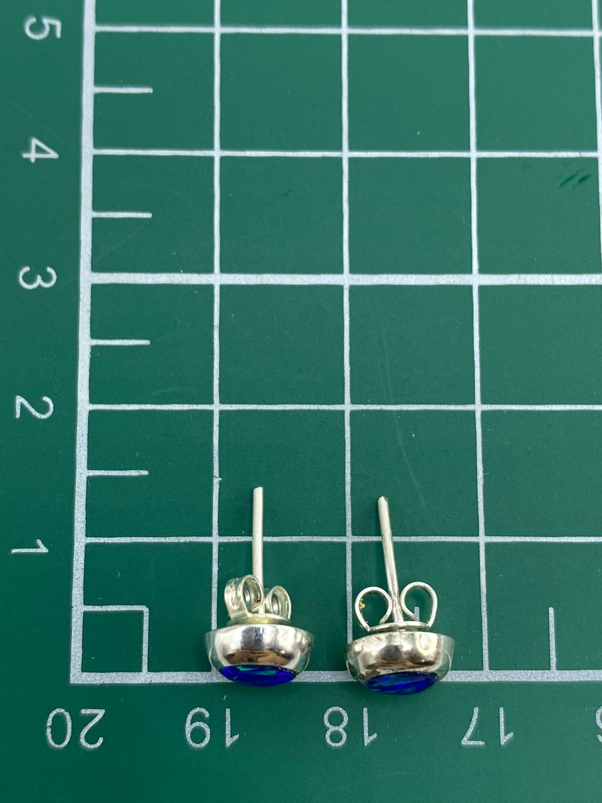 Aretes sobre fondo azul mostrando el brillo natural del ópalo de fuego
