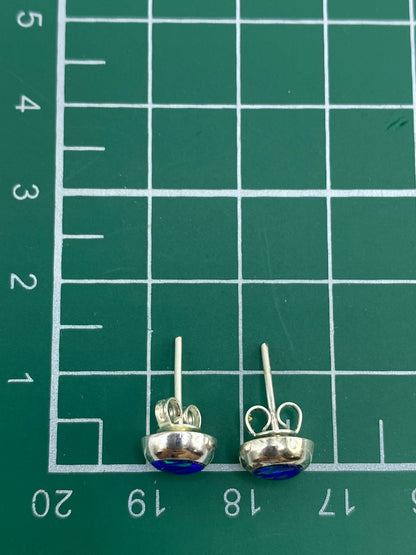 Aretes sobre fondo azul mostrando el brillo natural del ópalo de fuego
