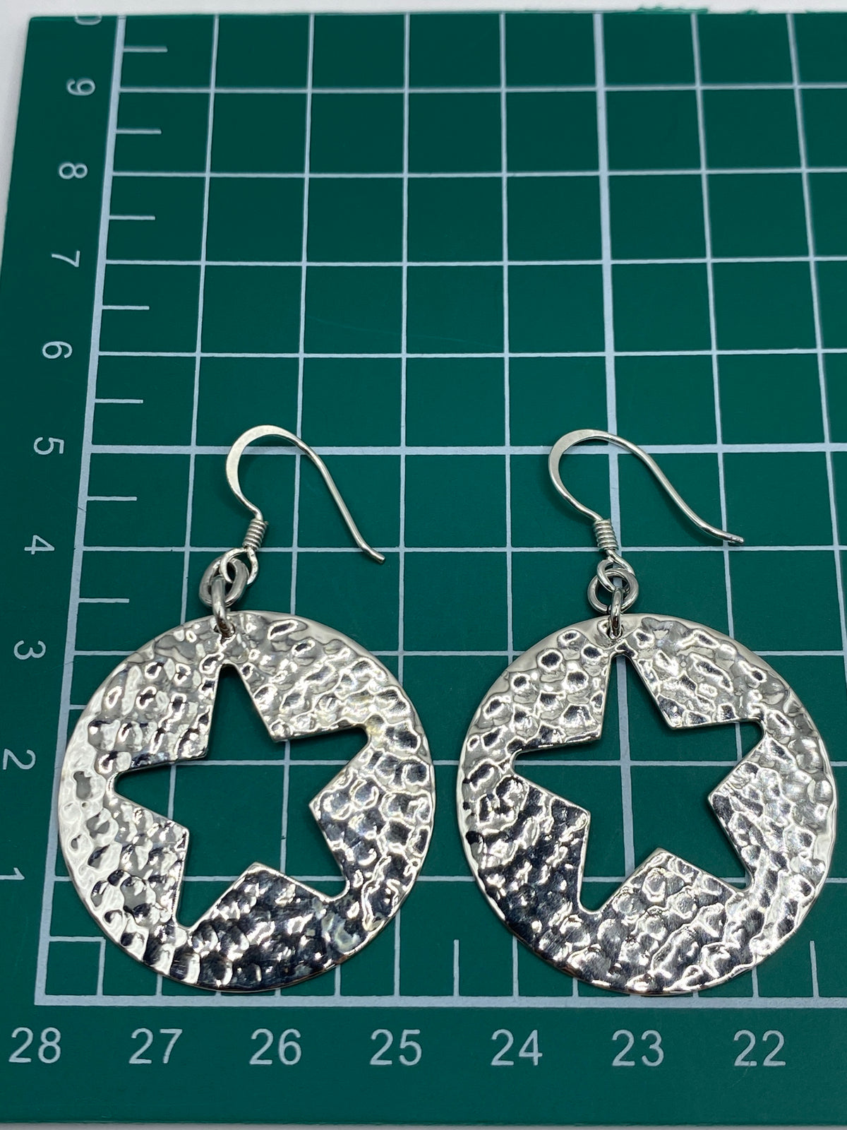 Aretes de plata con diseño de estrella abierta sobre fondo blanco, vista lateral