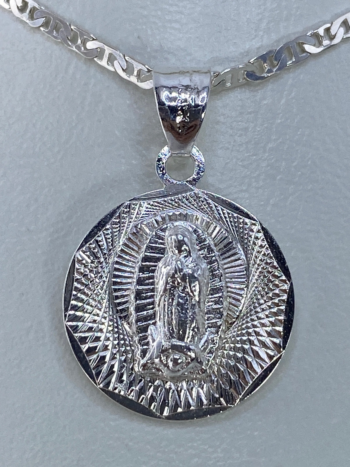 Dije Virgen de Guadalupe en plata 925 con relieve repujado, colgando de cadena plateada