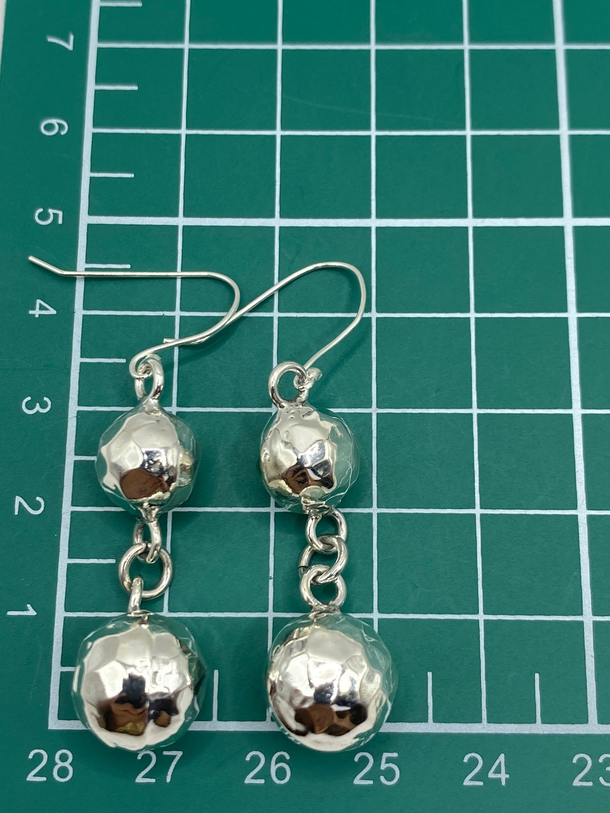 Aretes sobre regla de medición mostrando el largo de 5.1 cm del par