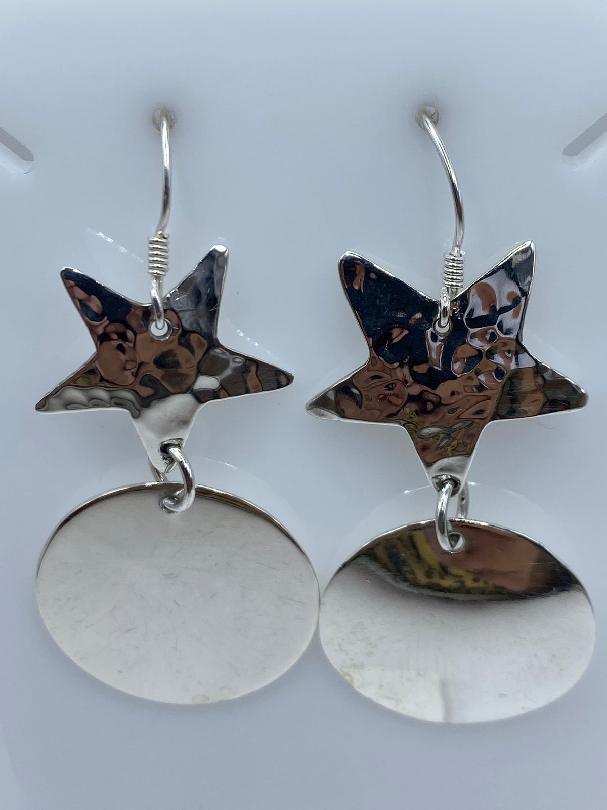 Par de aretes de plata 925 con estrella martillada superior y disco espejo pulido inferior, colgando del gancho