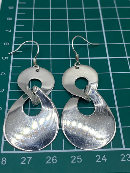 Aretes de plata calado comparados con escala métrica para referencia de tamaño