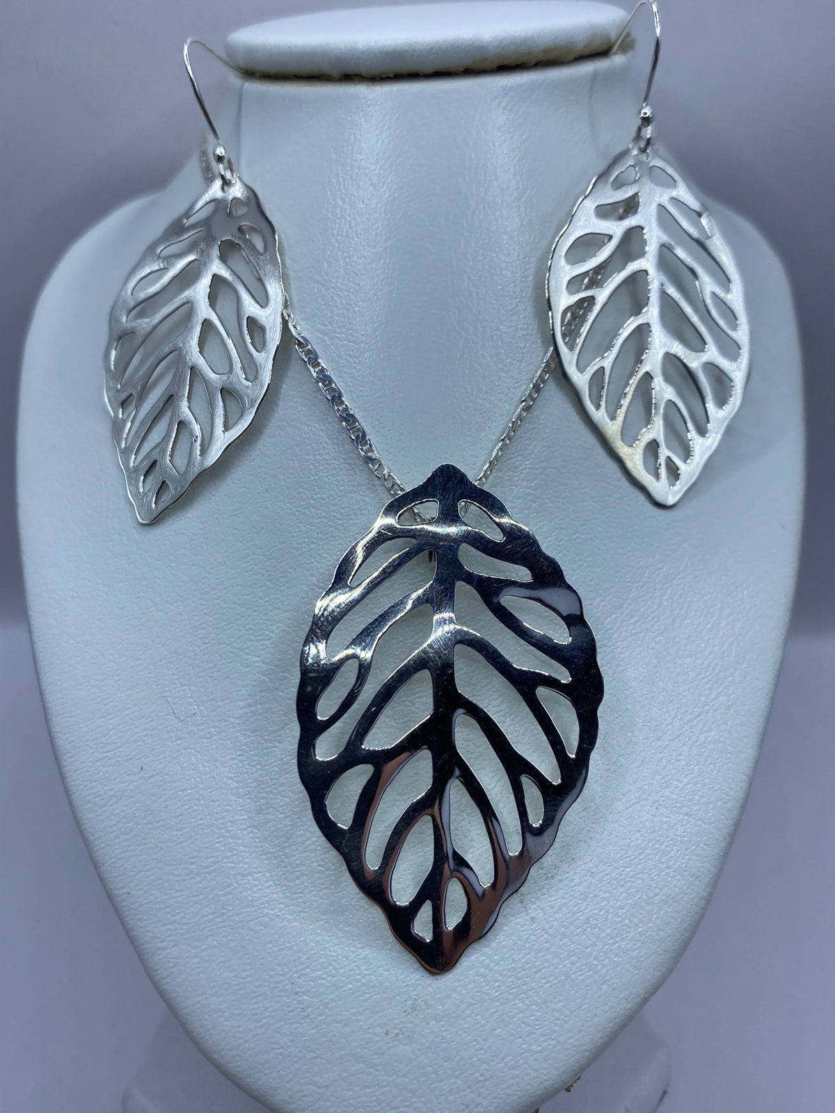 Aretes de plata calados en forma de hojas, colgando en gancho de plata
