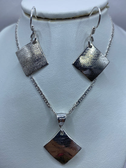 Detalle de la textura repujada en los aretes de plata con cierre de gancho