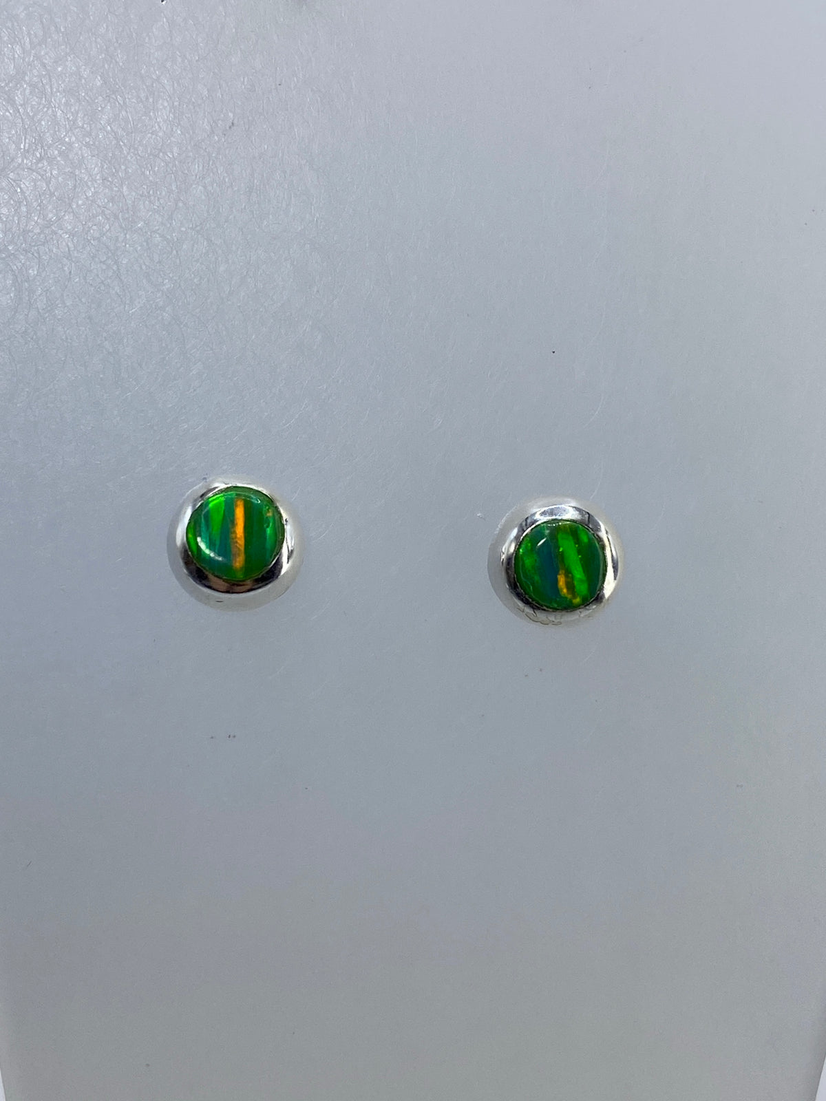 Detalle de los aretes mostrando los destellos multicolor del ópalo