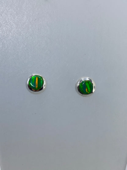 Detalle de los aretes mostrando los destellos multicolor del ópalo
