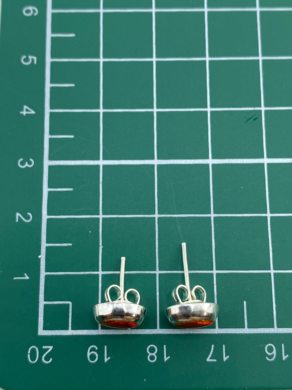 Comparación de tamaño: aretes junto a moneda para escala