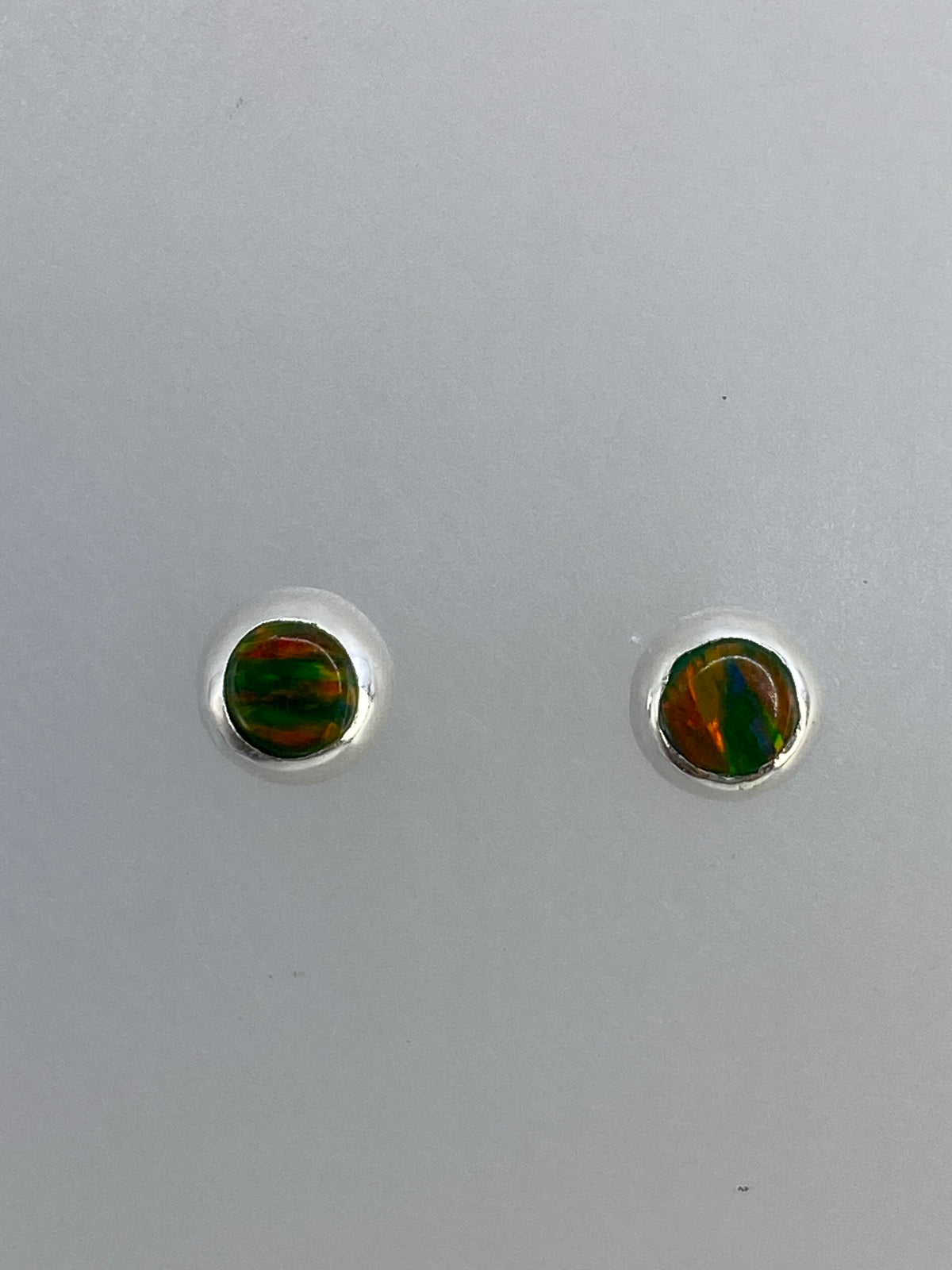 Detalle de cada arete de ópalo de fuego con engaste de plata a mano