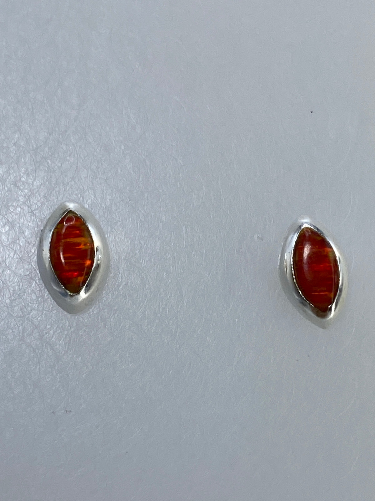 Aretes de plata 925 con ópalo de fuego en vista lateral, mostrando el engaste a mano
