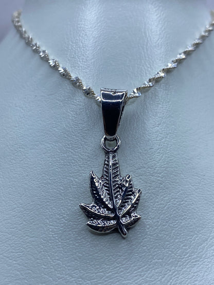 Detalle frontal del dije de hoja de cannabis mostrando el relieve en plata maciza
