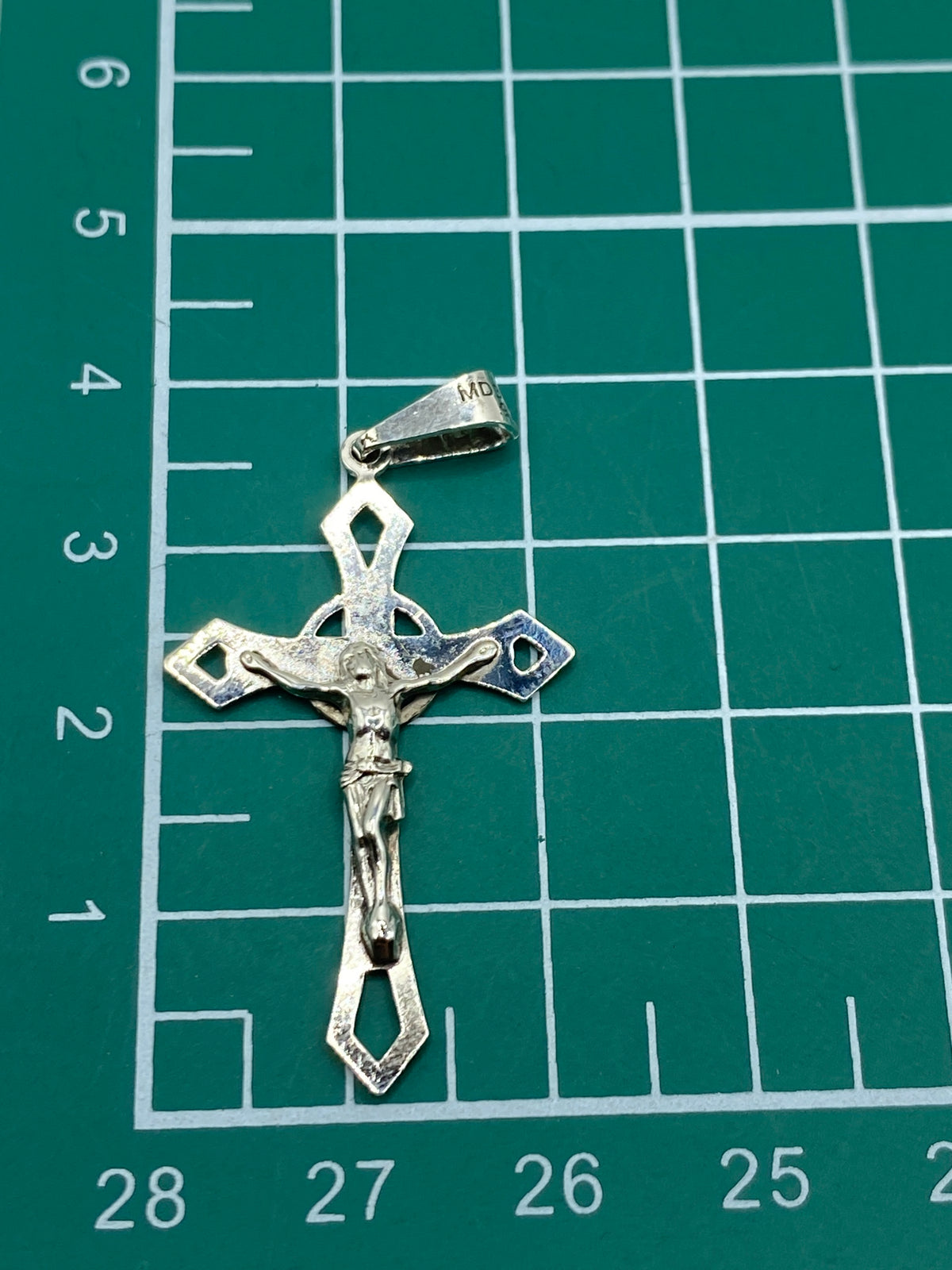 Crucifijo de plata 925 en balanza de joyero confirmando 1.36 gramos