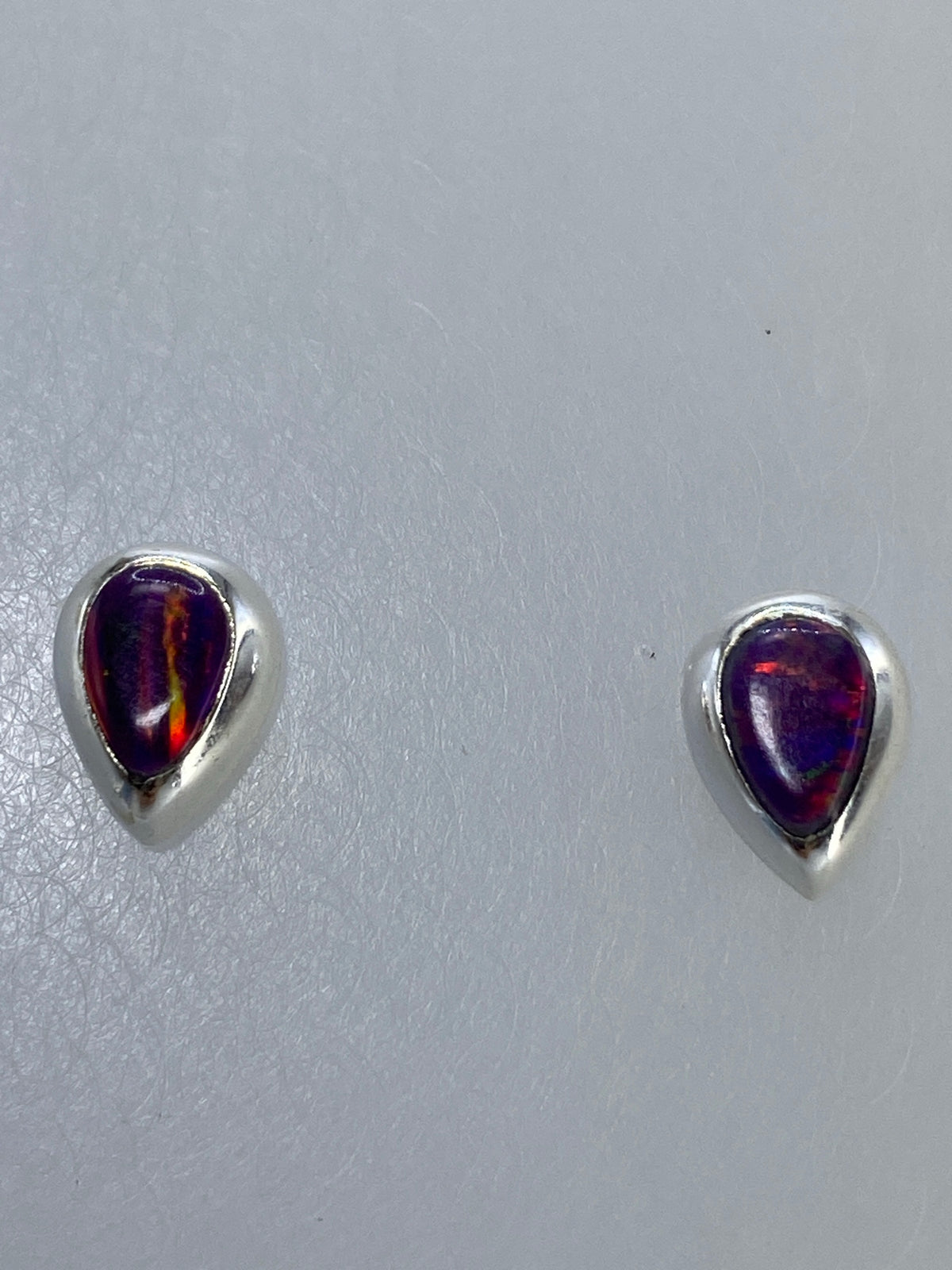 Aretes de plata colgando sobre regla de centímetros para mostrar tamaño