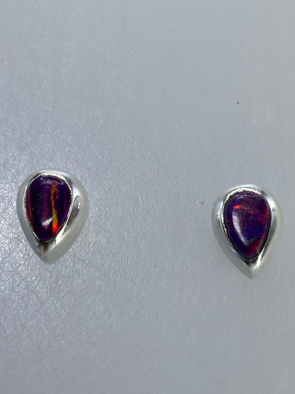Aretes de plata colgando sobre regla de centímetros para mostrar tamaño