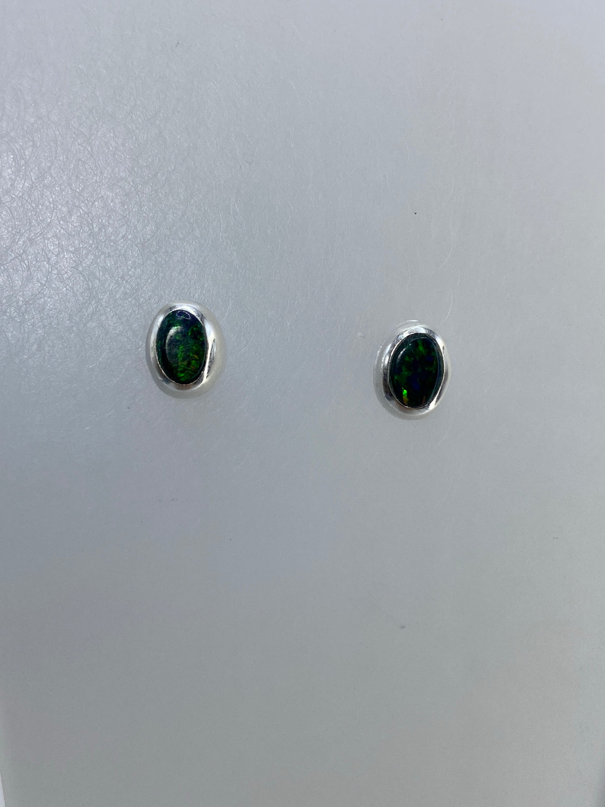 Detalle frontal de los aretes mostrando el brillo verde del ópalo de fuego