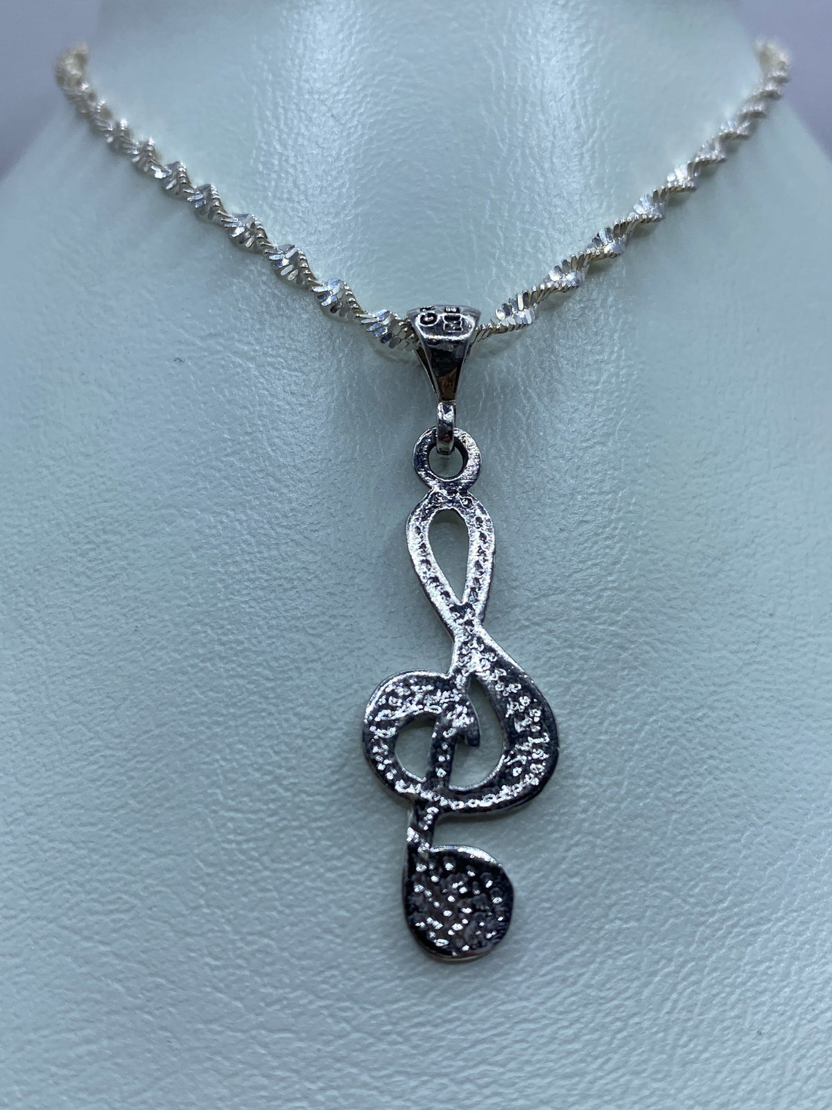 Detalle de la nota musical en plata pulida, vista de frente