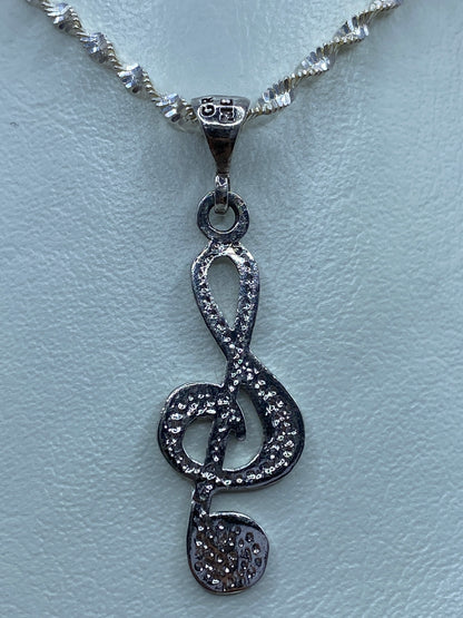 Dije de plata nota musical sobre regla métrica mostrando tamaño de 3.7 cm