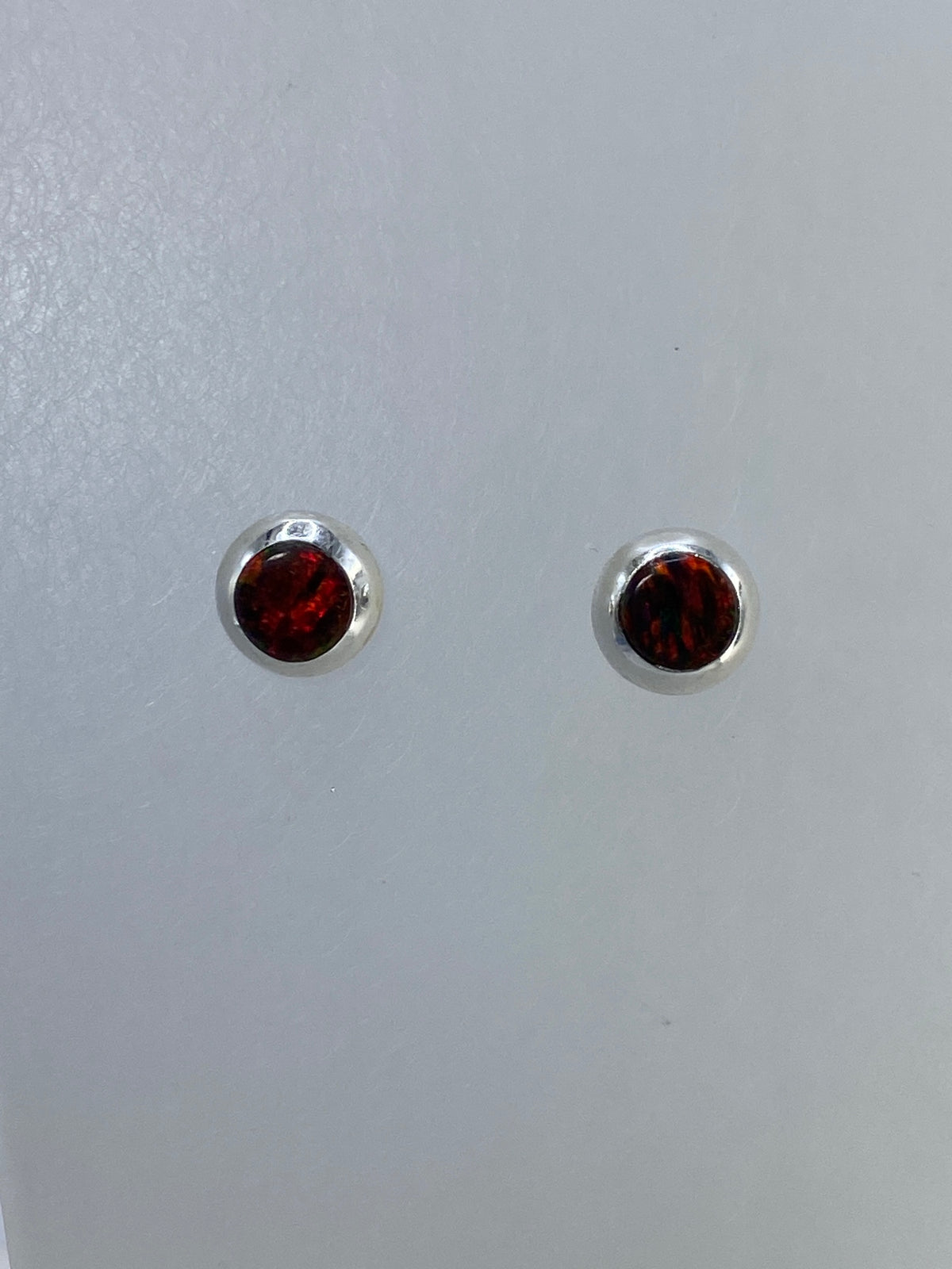 Detalle frontal de los aretes mostrando el brillo cafe del opalo de fuego
