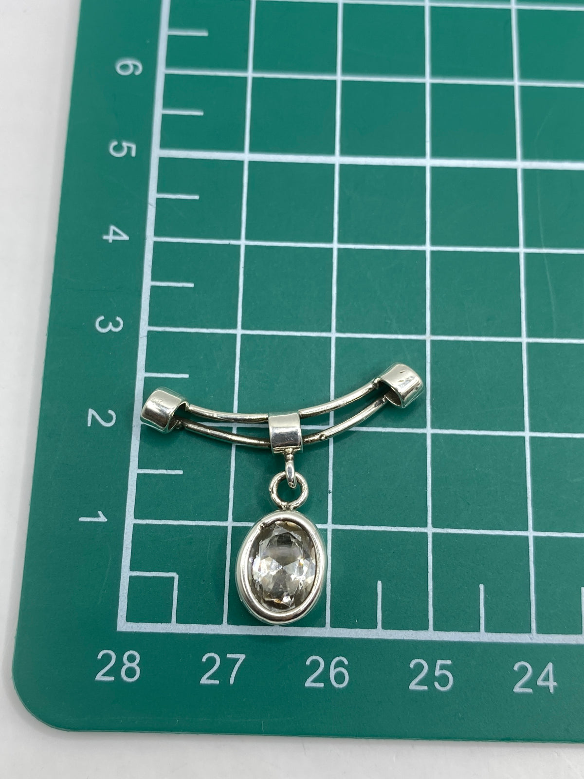 Dije de plata sobre escala de peso mostrando 2.57 gramos