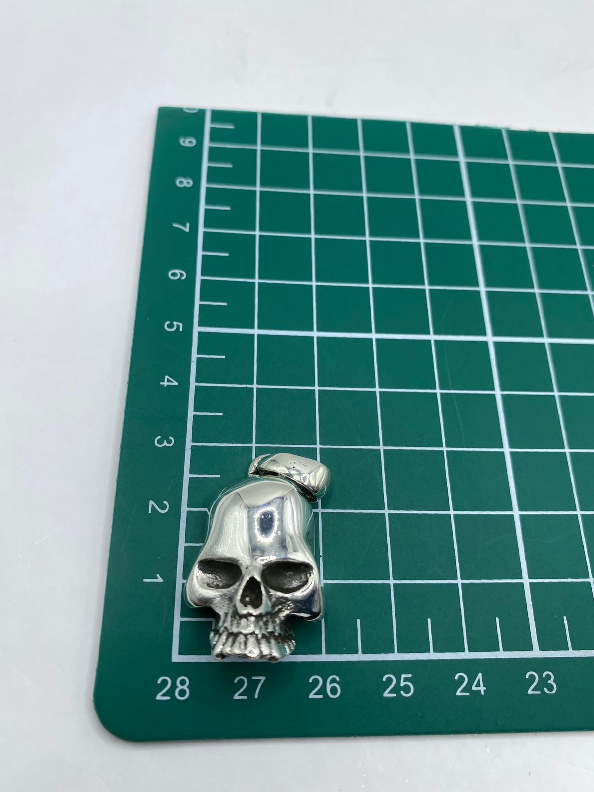 Calavera de plata de 4 cm al lado de escala de centímetros mostrando tamaño real