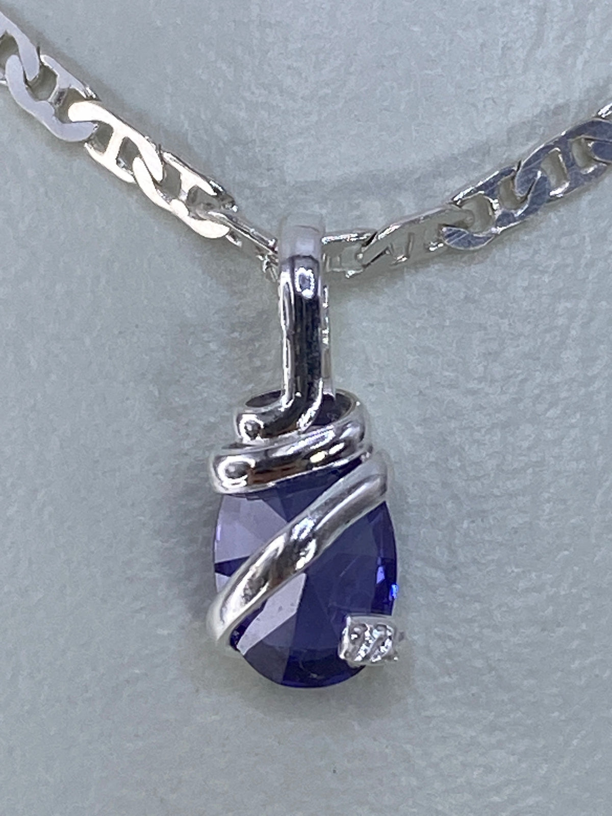 Dije de circonia azul de 1.4 cm de largo sobre escala milimétrica