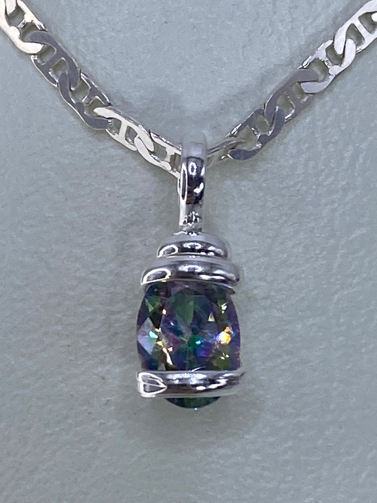 Dije de plata con circonia multicolor engastada, colgando de cadena plateada de eslabones