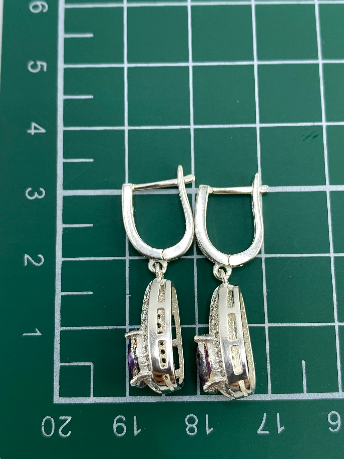 Aretes en estuche azul sobre balanza de precisión mostrando 4.85 gramos