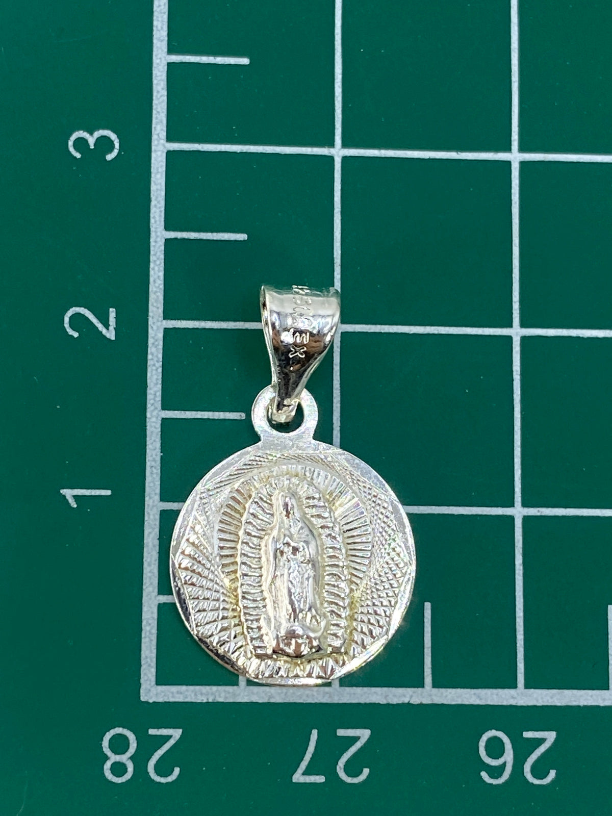 Dije junto a una moneda de referencia de tamaño, mostrando 2.2 cm de largo