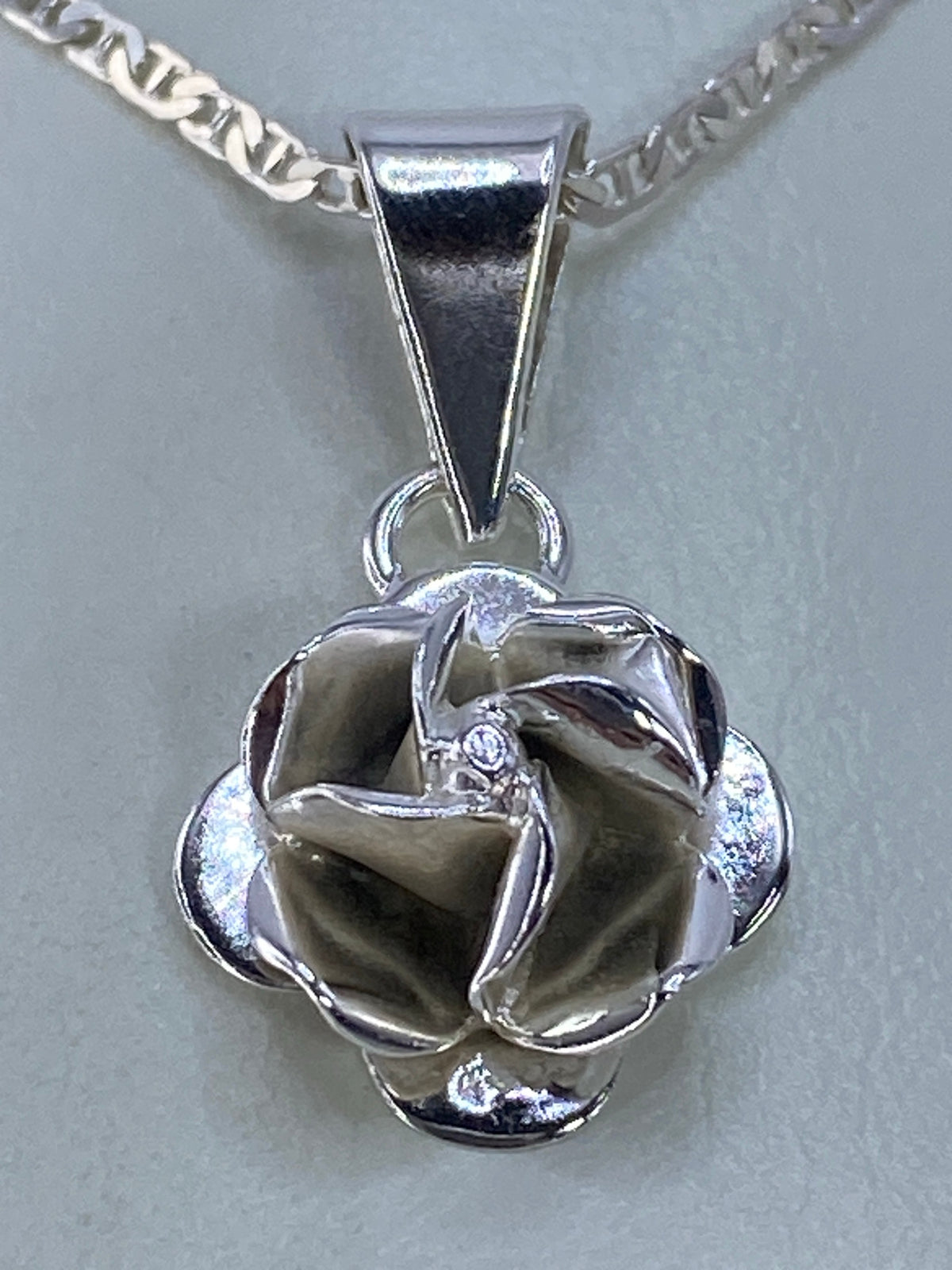 Vista frontal del dije floral en plata 925, detalles en relieve iluminados