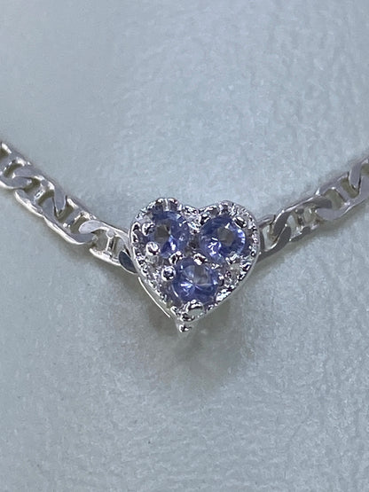 Primer plano del corazón de circonia morada en plata pulida, detalle del engaste