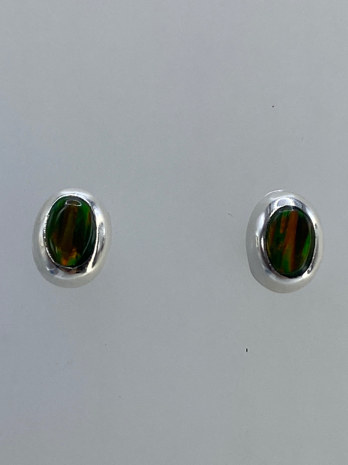 Aretes en la mano mostrando el tamaño real y el brillo del ópalo