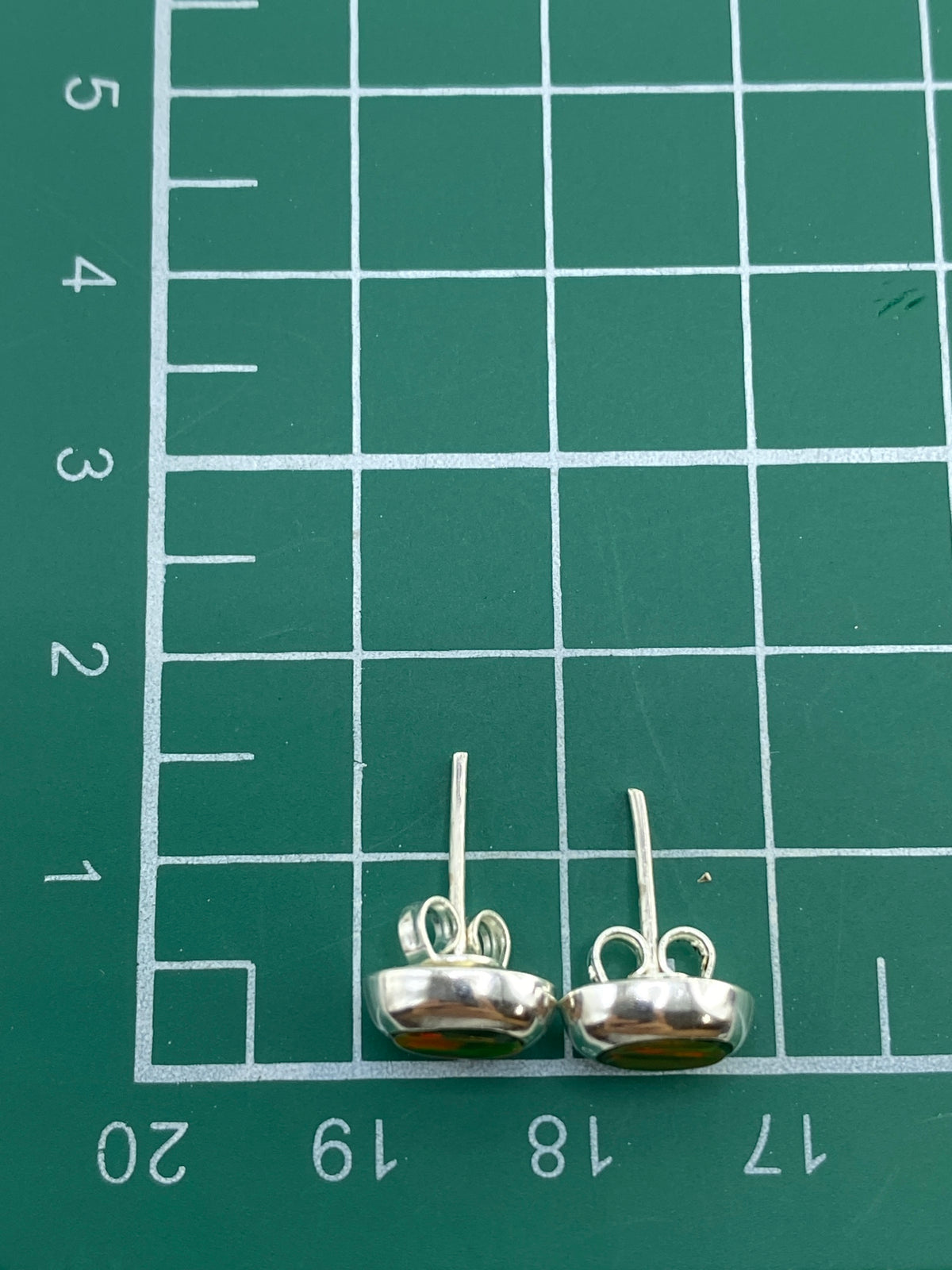 Aretes de plata 925 sobre fondo blanco con el Quinto visible