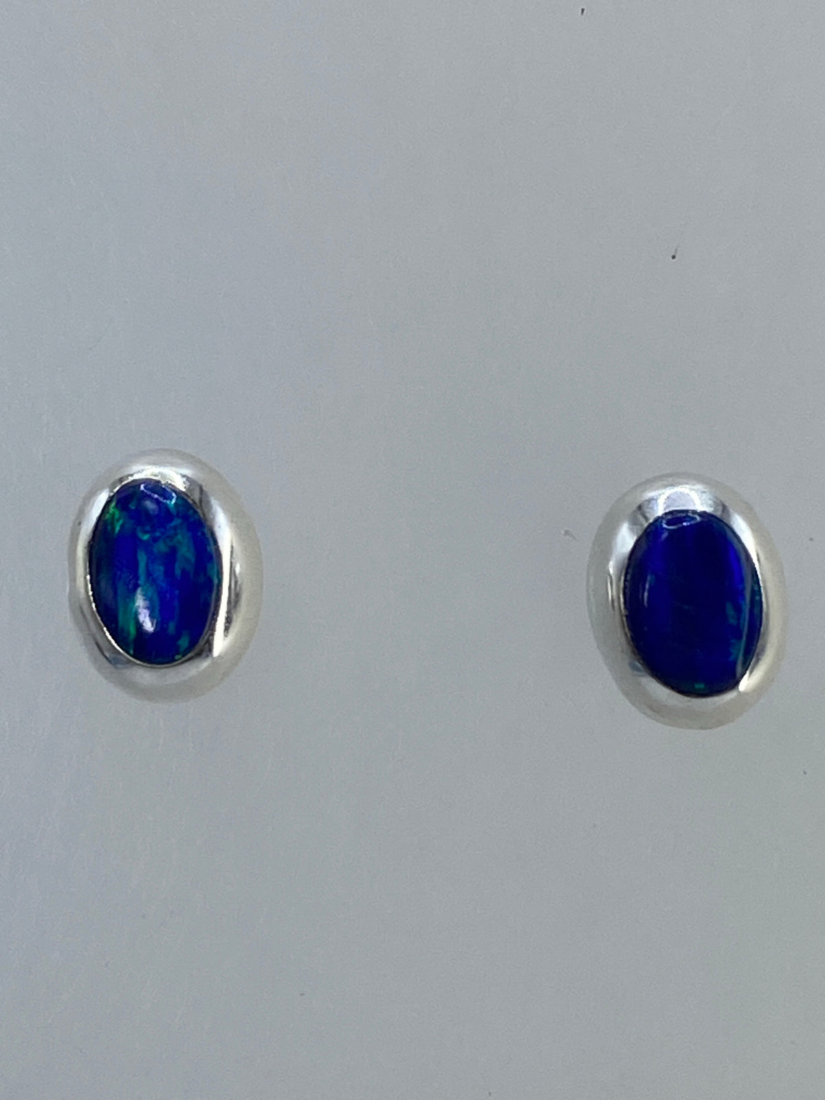 Aretes de plata con ópalo de fuego multicolor mostrando destellos naranjas y azules