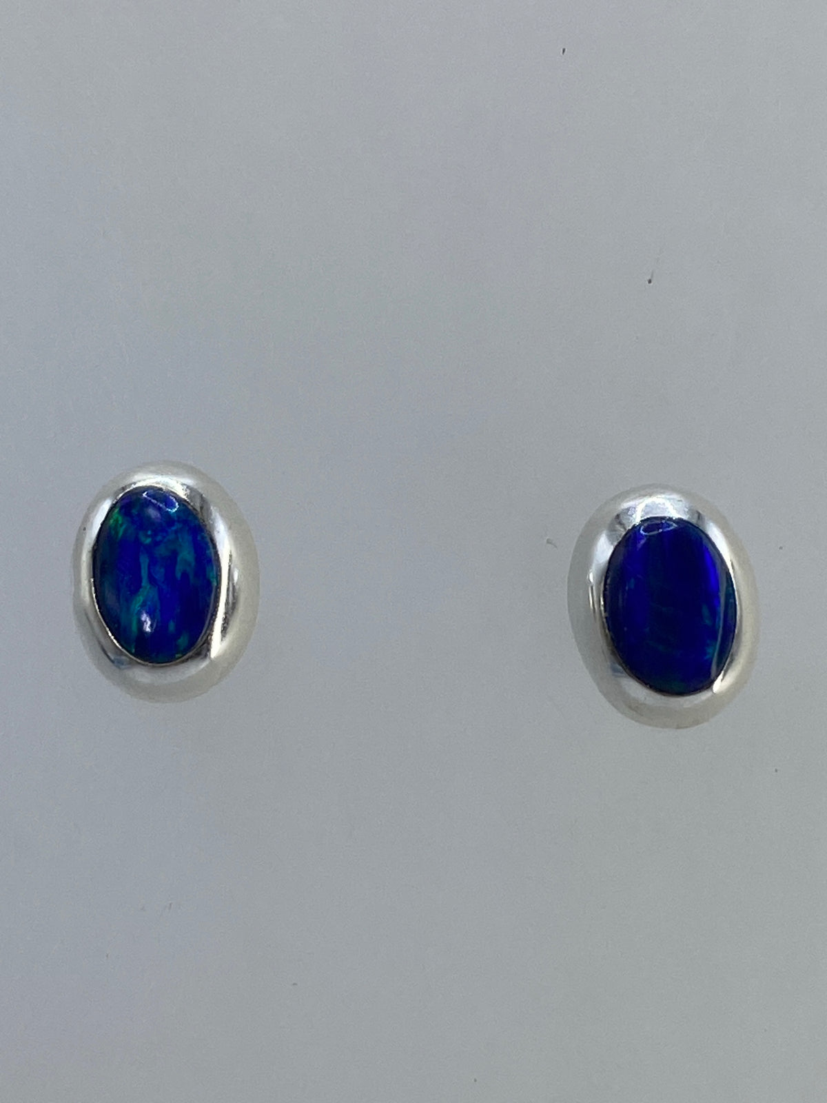 Aretes tipo botón con poste y mariposa en vista frontal