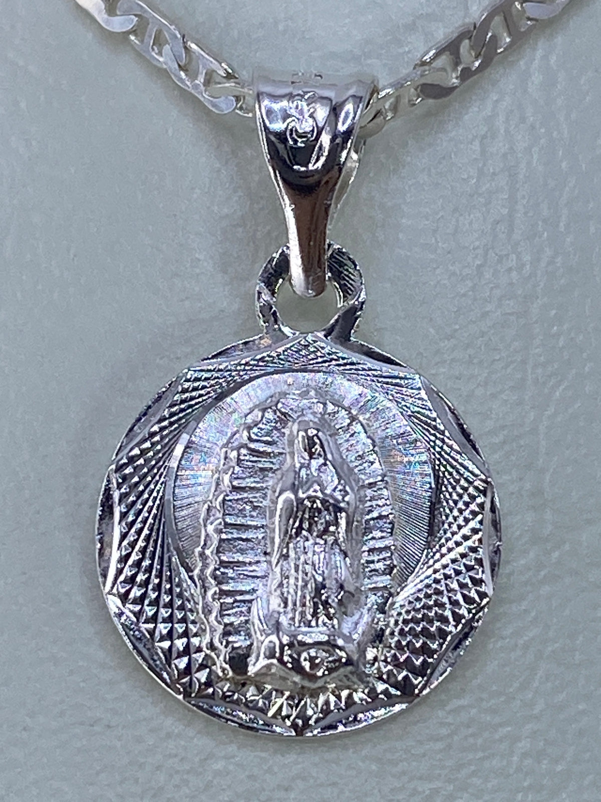 Detalle del repujado a mano: rostro y manto de la Virgen con rayos de luz