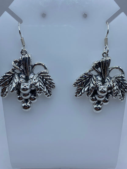 Aretes de plata con forma de racimo de uvas, técnica de granulado, colgando de ganchos de plata