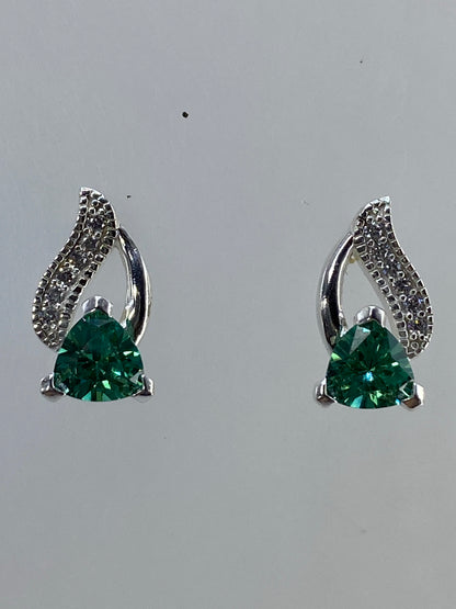 Par de aretes de plata 925 con alas de ángel y circonia verde esmeralda sobre fondo neutro