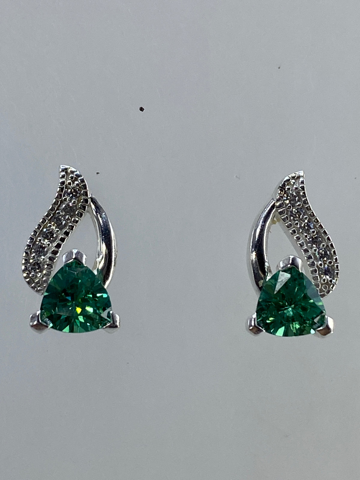 Aretes de plata con alas enmarcando la circonia, vista lateral frontal