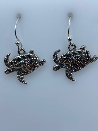 Aretes de plata con tortuga marina en relieve, par completo sobre fondo blanco