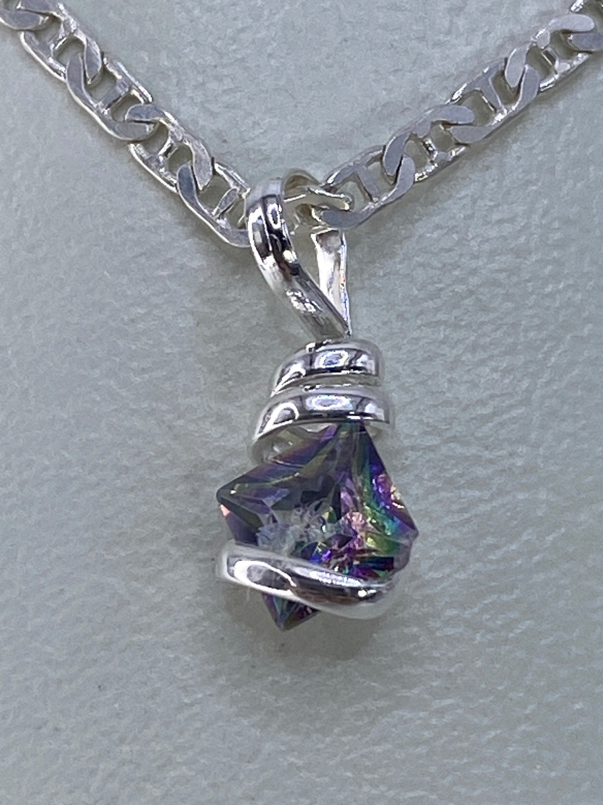 Circonia multicolor engastada en plata mostrando destellos de azul, púrpura y amarillo
